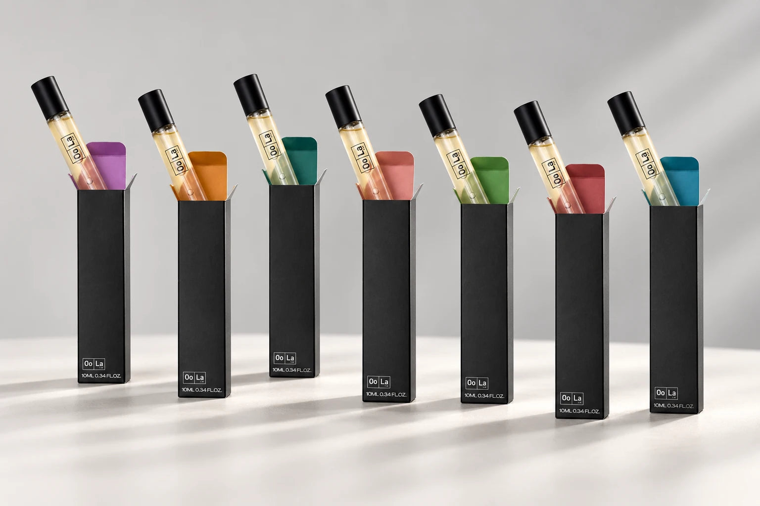 Seven 10ml fragrances in black cartons with different coloured interiors
